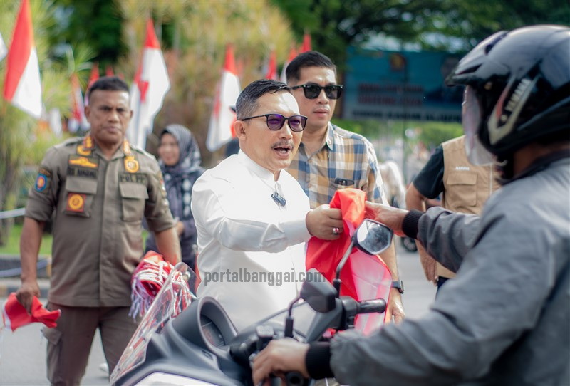 Bupati Banggai Amirudin membagikan bendera merah-putih kepada warga yang melintas di jalan raya